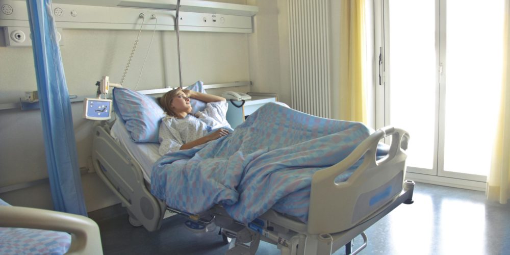 Hospital bed in ward with person in it