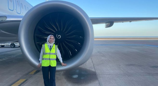 Sandwell alumna Maya Ghazal standing in front of a plane on the runway